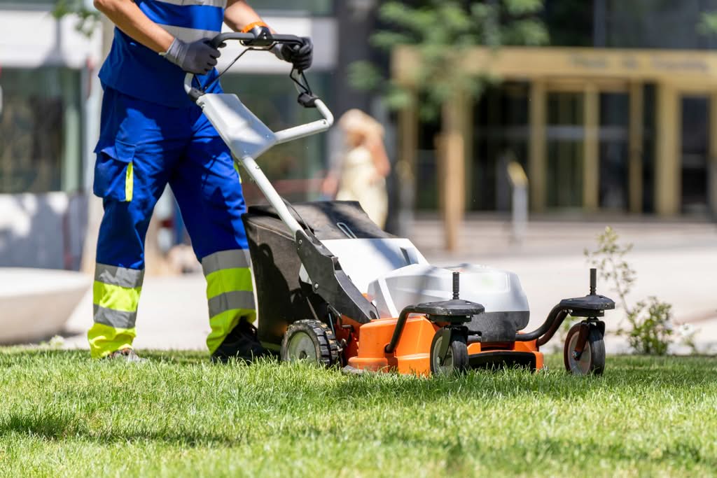 A maintenance technician providing professional lawn mowing services on a green lawn in an urban setting in Ocala, FL.
